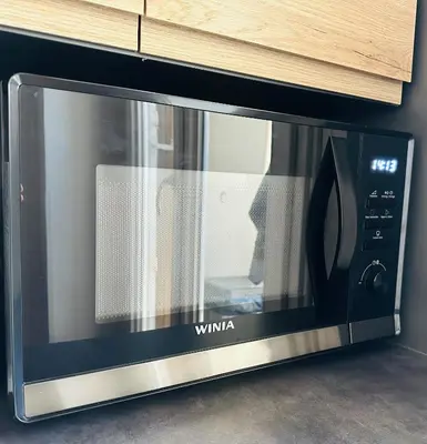 a microwave oven is sitting in a cabinet at The NICE - 3 rooms, 3air cond, 3TV, 3fans, 2 wc, WIfi everywhere 5min aeroport, train, beach, 1min tram, 15 min centre, port, parking possible in Nice
