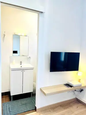 a white bathroom with a sink and a mirror at LE RAPHAEL - Studio à 10 min de la mer - Wifi et Climatisation in Nice