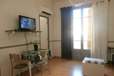 a living room with a table and a television and a window at Studio Climatisé dans villa bourgeoise in Nice