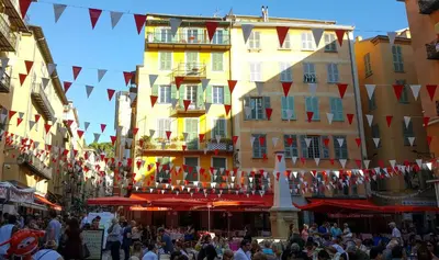 a busy street in a city with people and flags at Très joli loft au cœur de Nice in Nice