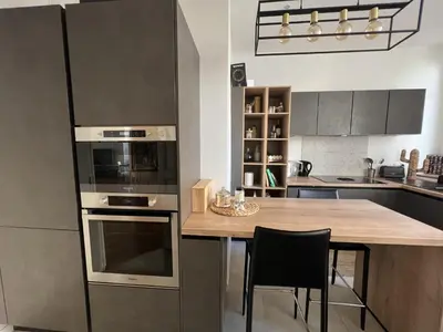 a kitchen with a wooden table and a large refrigerator at Luxueux Appartement 115m2, 3 Chambres centre ville avec parking à 5 min plage -climatisation in Nice