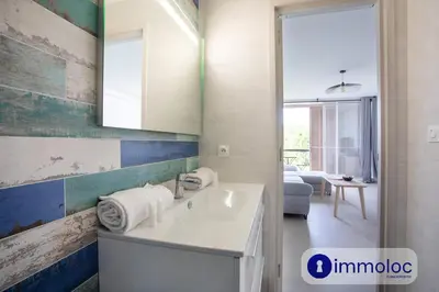 a bathroom with a sink and a living room at Air-conditioned studio 5 minutes from the beach and shops in Cros-de-Cagnes