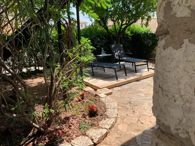 a patio with a bench and a table in a garden at Appartement 1pièce avec jardin dans Mas de Caractère in Saint-Laurent-du-Var