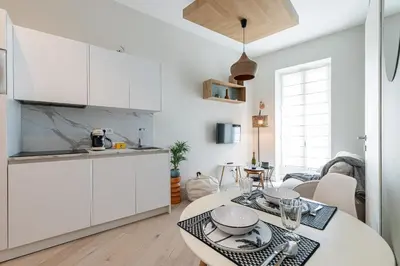 a kitchen with white cabinets and a table with dishes on it at Charming Central 1 Bdr in Nice
