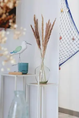 a white shelf with a vase with a bird on it at Appartement 2 pieces in Nice