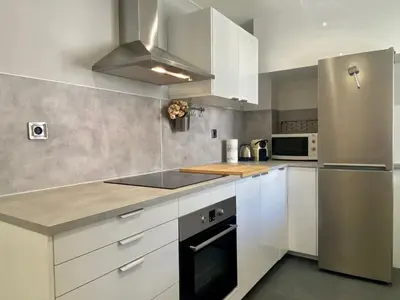 a kitchen with white cabinets and a stainless steel refrigerator at Suite Gloria Five stars holiday house in Nice