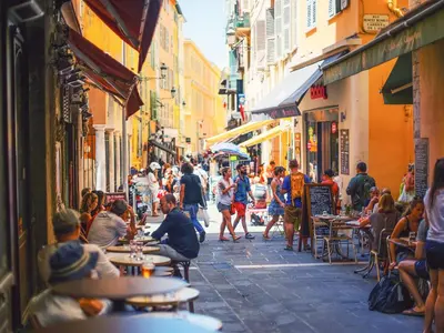 a group of people sitting at tables on a street at Cosy 2 pieces rénové, Proche mer, 4 pers in Nice