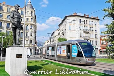 a train on a street with a statue of a man at Cosy appartement en plein coeur de la libération in Nice