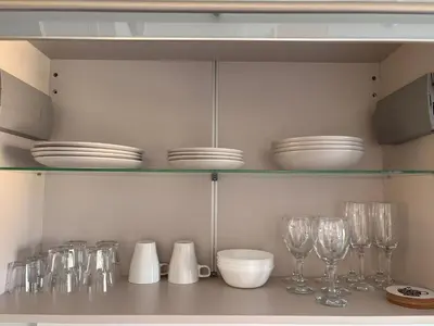 a kitchen with plates and glasses on a shelf at Charmant apt calme - proche plage et aéroport - climatisé - parking privé gratuit in Cagnes-sur-Mer
