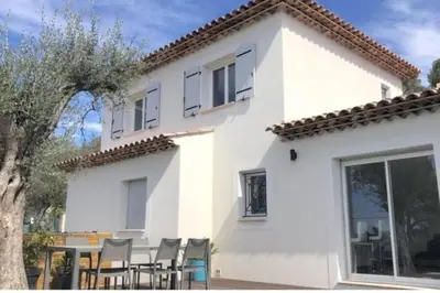 a white house with chairs and a table in front of it at Nice, Magnifique villa vue mer avec piscine in Nice