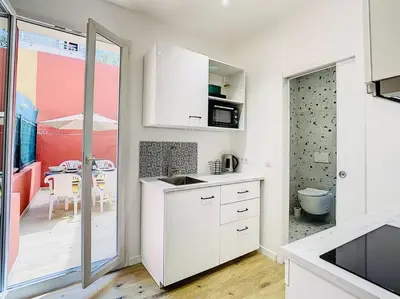 a kitchen with white cabinets and a dining room at Appartement Terrasse Proche Port et Plages de Nice in Nice