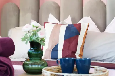 a table with pillows and a vase with flowers at Nice Renting - CAMBRAI03 - Seaside Studio on the Promenade des Anglais in Nice