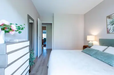 a white bedroom with a bed and a vase of flowers at Happyfew Sainte Anne in Nice