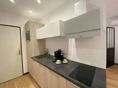 a kitchen with white cabinets and a black counter top at Charming Apartment in Nice in Nice
