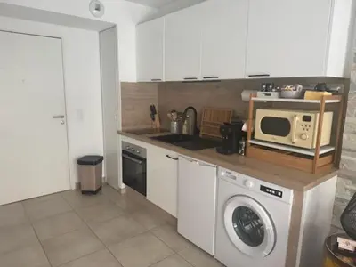 a kitchen with a washing machine and a microwave at Chez Candie in La Trinité