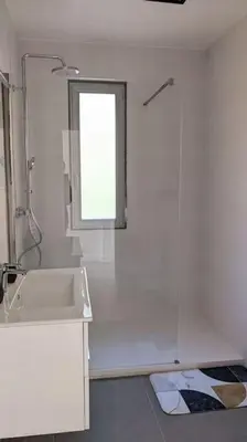 a white bathroom with a sink and a window at 3 pièces dans villa avec piscine in Nice