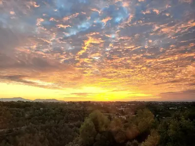 a sunset over a city with trees in the foreground at Studio climatisé vue imprenable wifi in Vence
