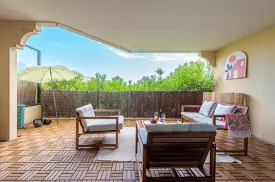 a patio with a couch and chairs and an umbrella at Happyfew Le Flora in Nice