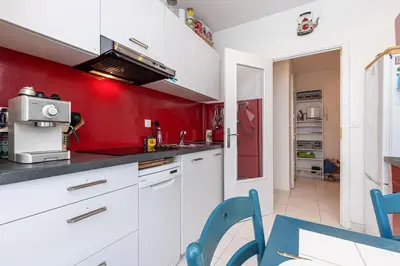 a kitchen with white cabinets and a red wall at The place to be in Nice in Nice