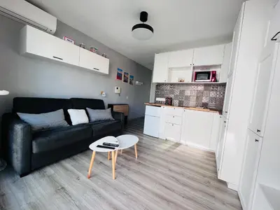 a living room with a black couch and a table at Studio terrasse et parking privé in Nice