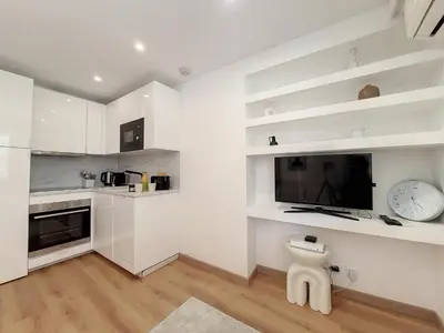 a white kitchen with white shelves and a tv at Nestor&Jeeves - COEUR RIVIERA - City Center - Near Beach in Nice