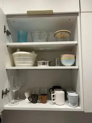 a white cabinet filled with dishes and bowls at Magnifique appartement moderne - Clim & Wifi in Nice