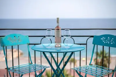 a table with two chairs and a bottle and two glasses at Le balcon de la baie des Anges in Nice