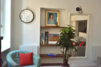 a living room with a clock on the wall and a chair at Apartment 33 on The Old Historic Senate Square in Nice