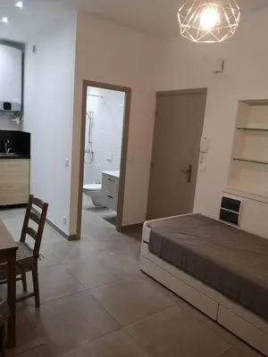 a bedroom with a bed and a table and a kitchen at maison de papa in Nice