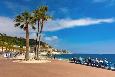 a group of people sitting on a beach with palm trees at Studio cosy in Nice