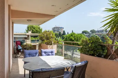 a patio with a table and chairs on a balcony at Flat with swimming pool close to the sea in Cagnes-sur-Mer