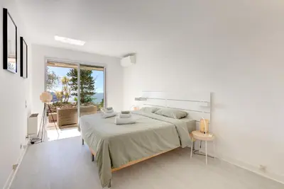 a white bedroom with a large bed and a window at Giant Terrace on a stunning View in Villefranche-sur-Mer