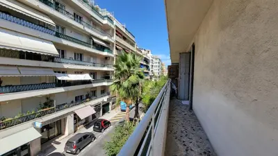 an apartment balcony with a palm tree and buildings at appartement neuf de 3 pieces avec climatisation in Nice