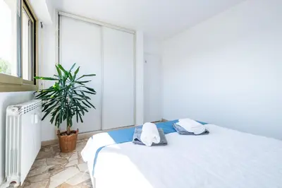 a bedroom with a white bed and a potted plant at Résidence méditerranée - Beachfront - Sun and Seaview - Pool - Private Parking in Cagnes-sur-Mer