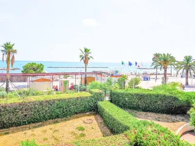 a park with bushes and palm trees and the beach at Horizon in Saint-Laurent-du-Var