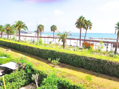 a garden with palm trees and the beach in the background at Horizon in Saint-Laurent-du-Var