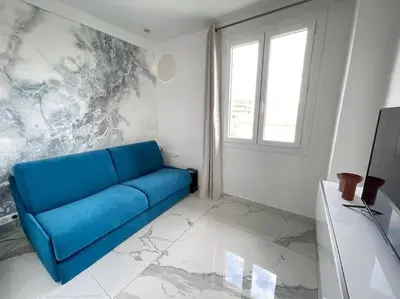 a blue couch in a white room with a window at Beach front, Superbe appartement pour 4 personnes in Nice