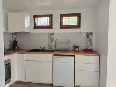 a kitchen with white cabinets and a white dishwasher at Joli 3p - Bas de villa in Saint-Andre-de-la-Roche