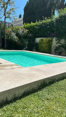 a swimming pool in the grass next to a building at Studio proche mer avec piscine Cros de cagnes in Cagnes-sur-Mer