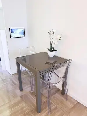 a glass table with two chairs and a vase with flowers at Promenade-des-anglais-front-sea in Nice