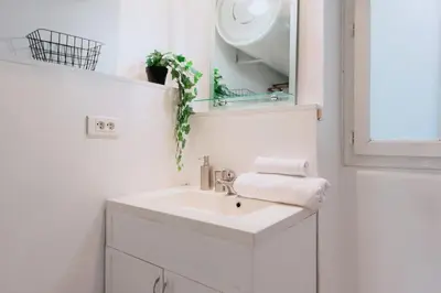 a white bathroom with a sink and a mirror at Grand appartement- Le Port A/C in Nice