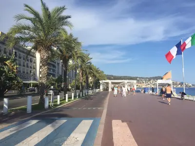 a street with palm trees and people walking down it at Promenade des Anglais /Carré d'or - 2 mins plages in Nice