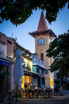 a clock tower with a table and chairs in front of a building at 3 pièces au cœur du cros de cagnes in Cagnes-sur-Mer
