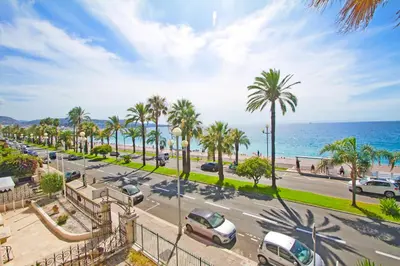 a view of a street with palm trees and the ocean at Luxury sea front suite Promenade in Nice