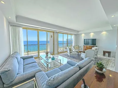 a living room with a blue couch and a view of the ocean at Panoramic Sea View Promenade in Nice