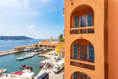 a building next to a marina with boats in the water at THE BAY AP4371 By Riviera Holiday Homes in Villefranche-sur-Mer