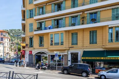 a yellow building with cars parked in front of a street at Charmant 3 pièces vue mer in Villefranche-sur-Mer