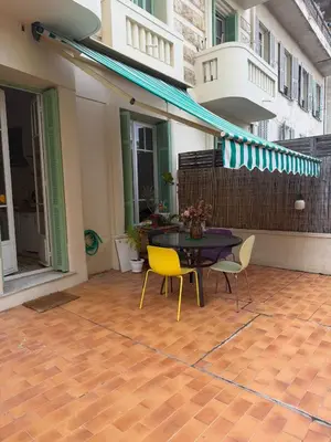 a patio with a table and chairs on a floor at Dolce bilocale con terrazzo in Nice