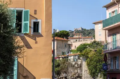 a building with green shutters on the side of a street at Cocon dans la vieille ville in Villefranche-sur-Mer