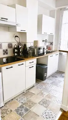 a kitchen with white cabinets and a tile floor at Studio calme Nice hyper centre in Nice